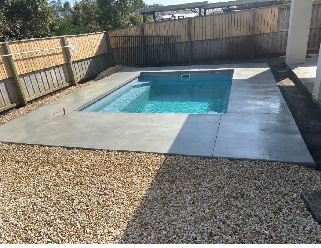 A Large Swimming Pool Is Sitting In Front Of A House  — Brodie Wynter Concreting in Port Macquarie, NSW