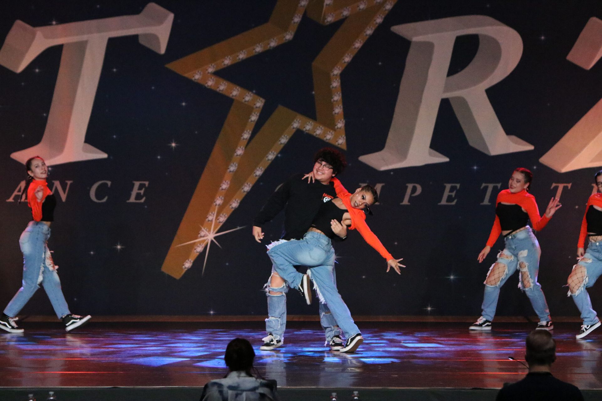A group of people are dancing on a stage in front of a sign that says tara
