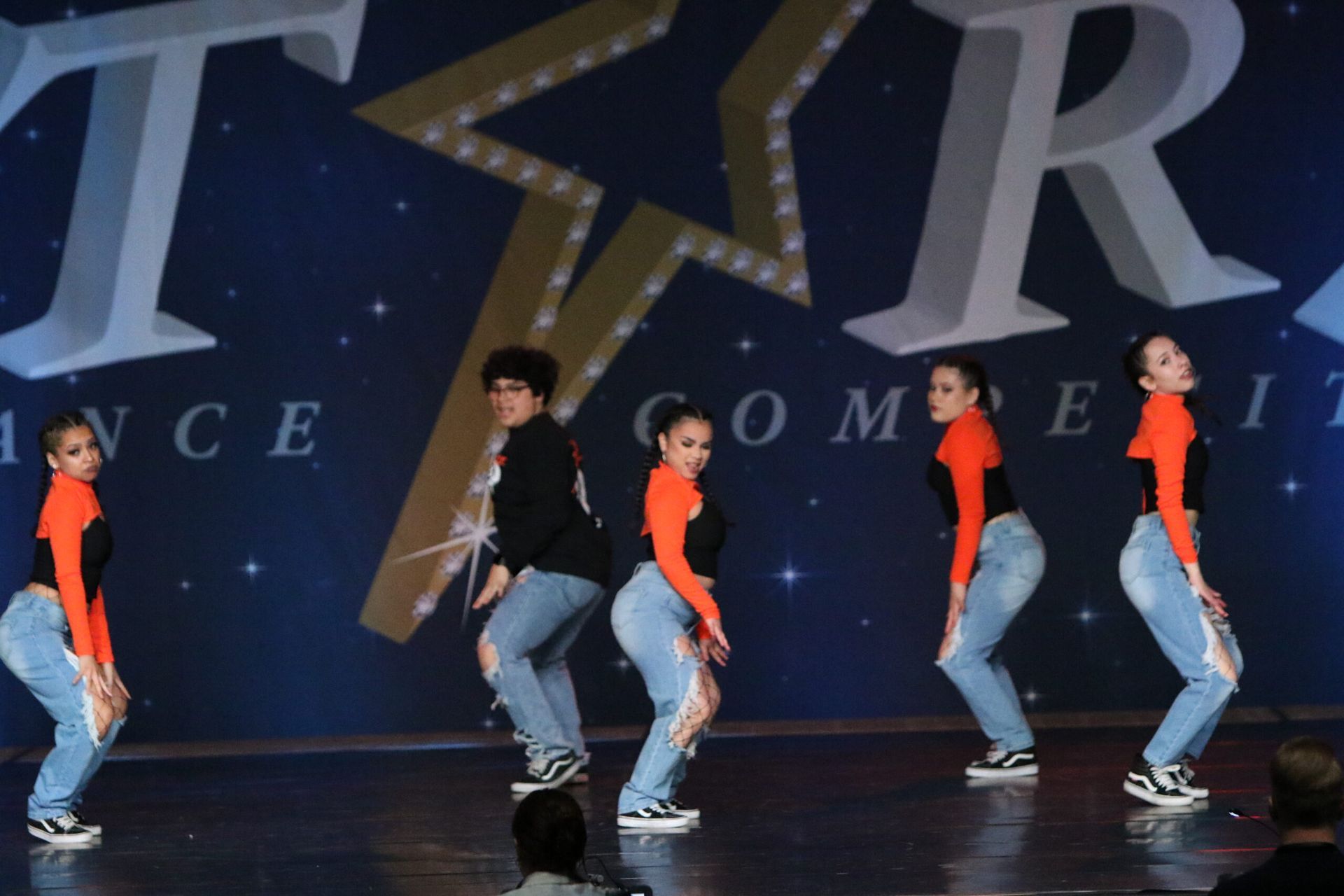 A group of dancers are performing in front of a sign that says t.r.