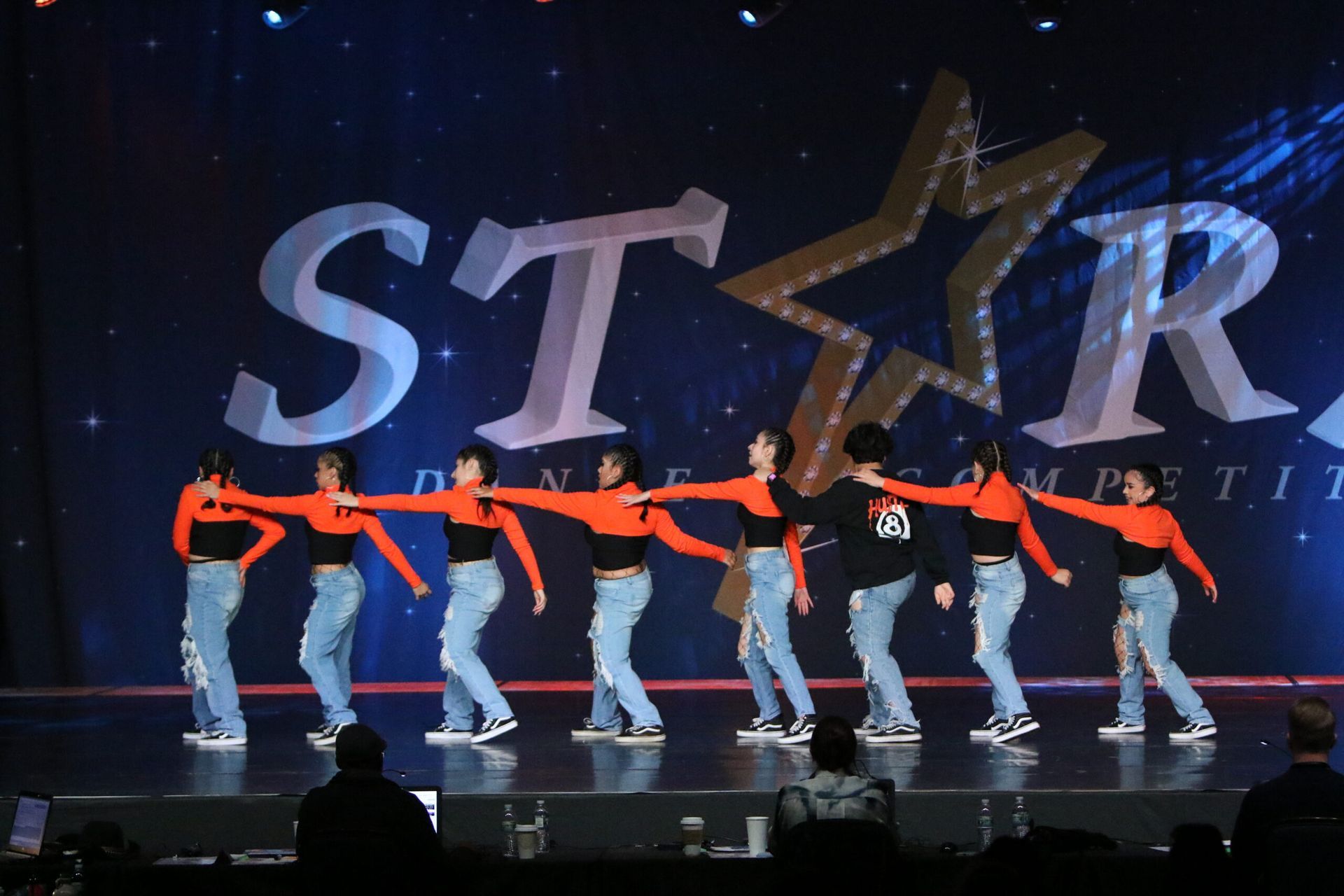 A group of people are dancing in front of a star logo