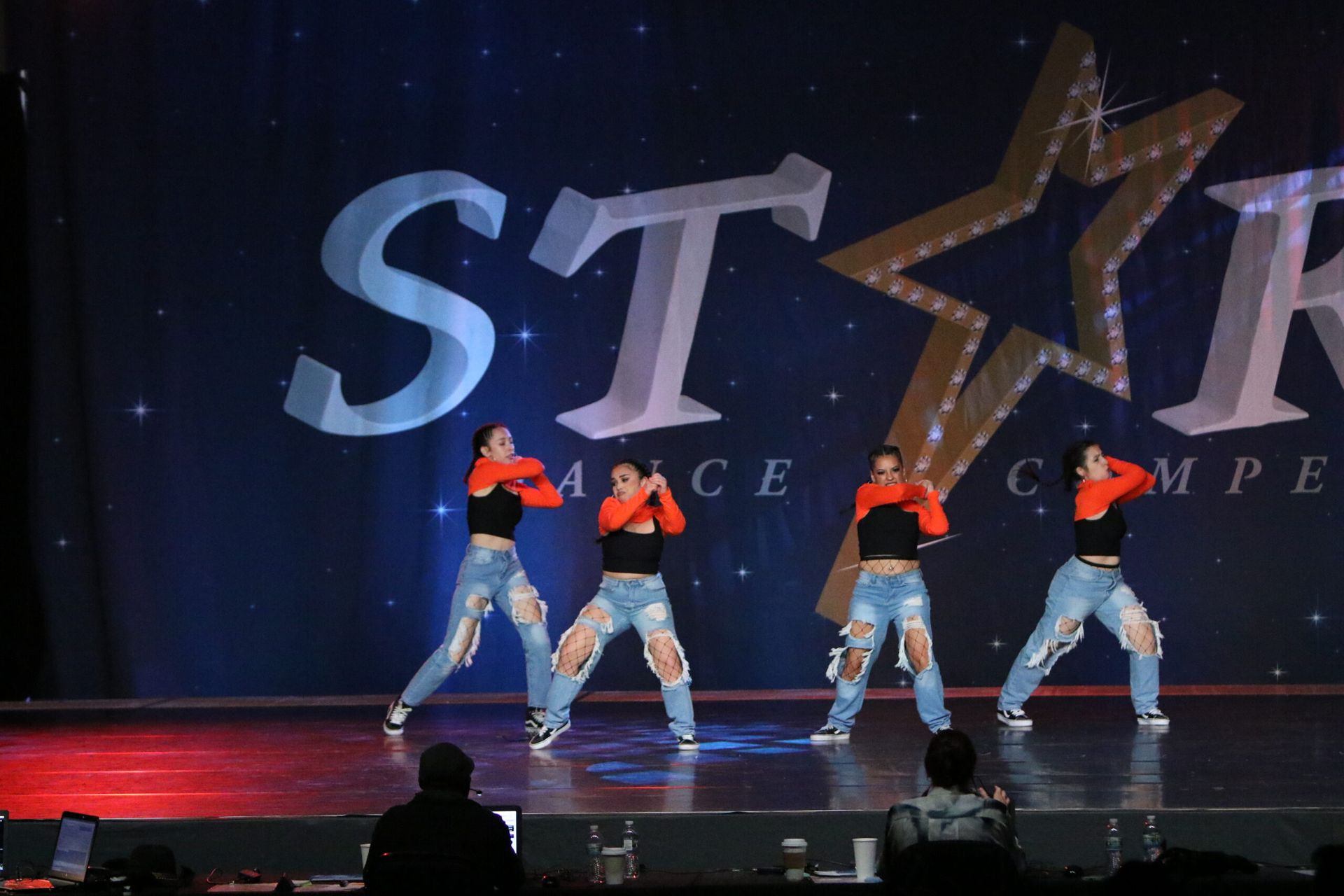 A group of women are dancing on a stage with the word star in the background