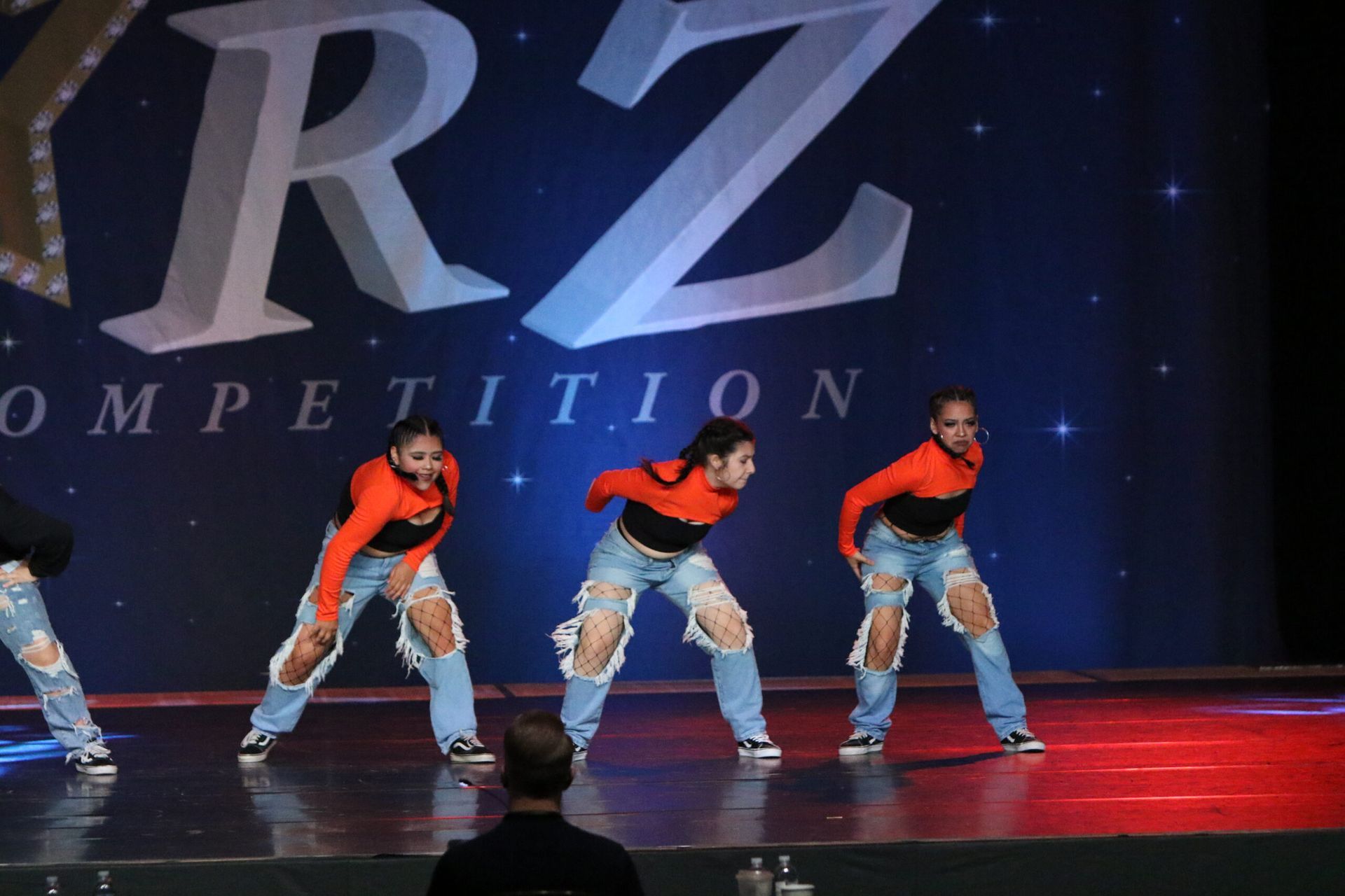 A group of dancers are performing on a stage in front of a rz competition logo
