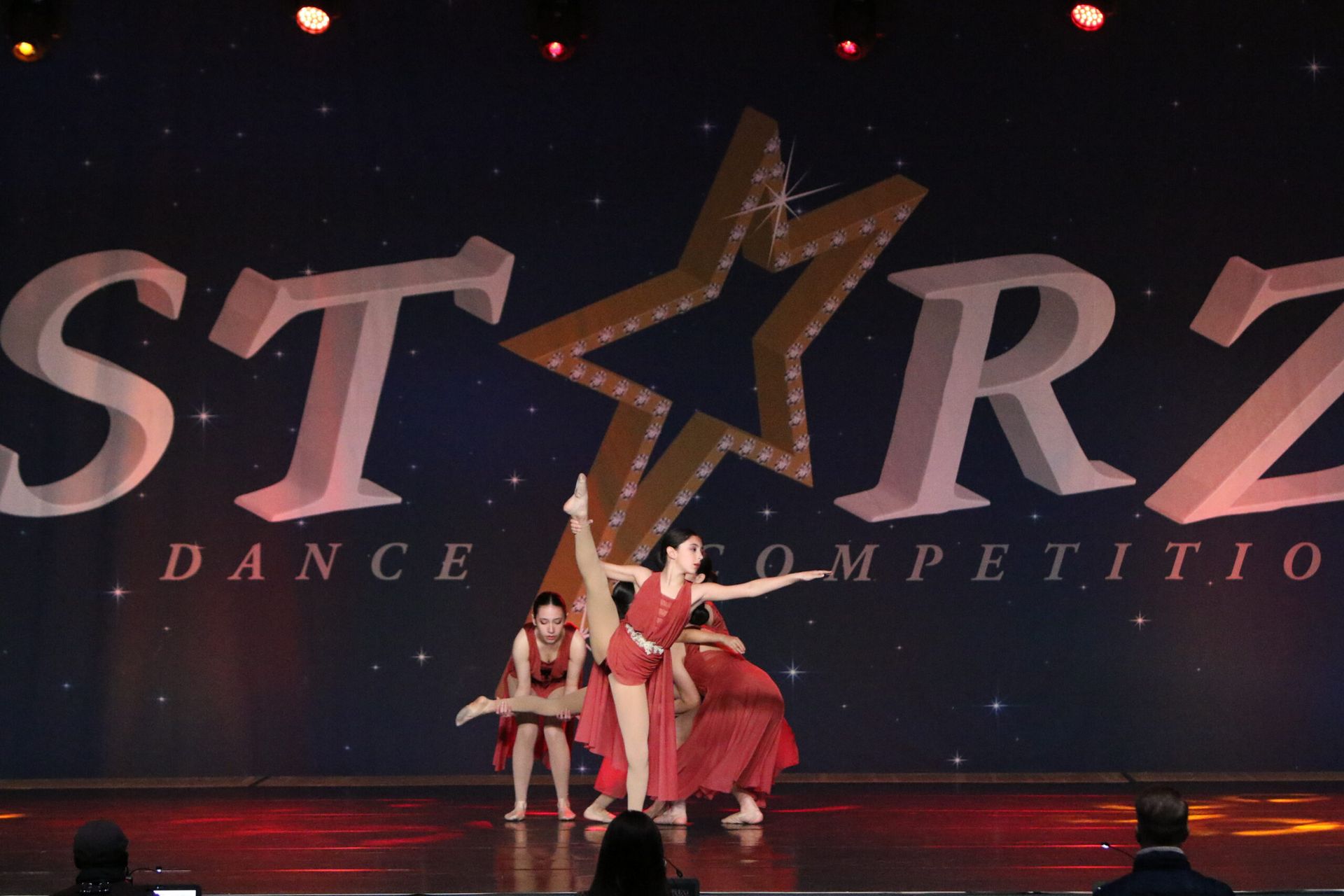 A group of dancers perform on stage in front of a starz dance competition logo