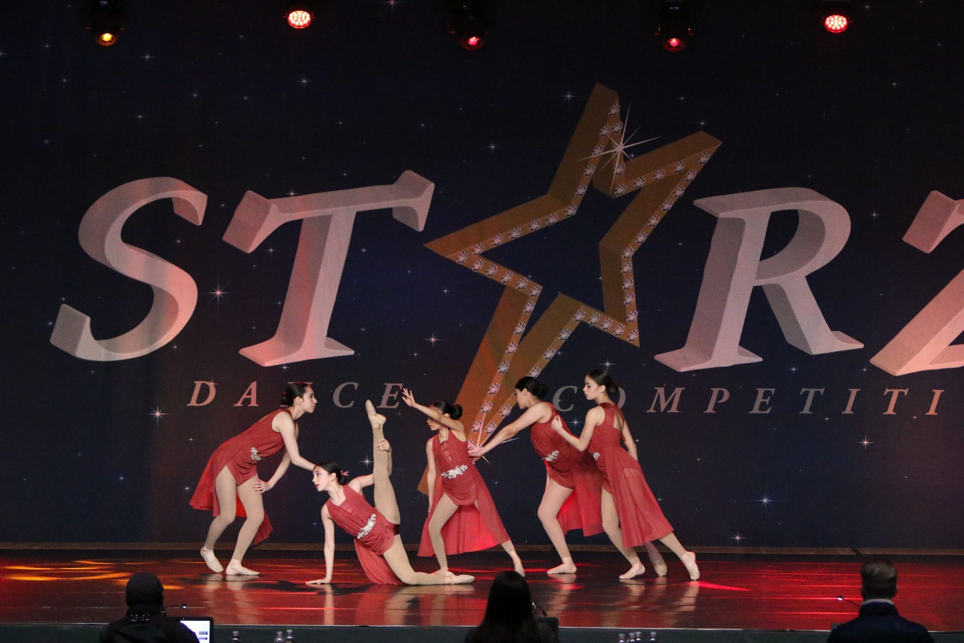 A group of dancers are performing in front of a sign that says star