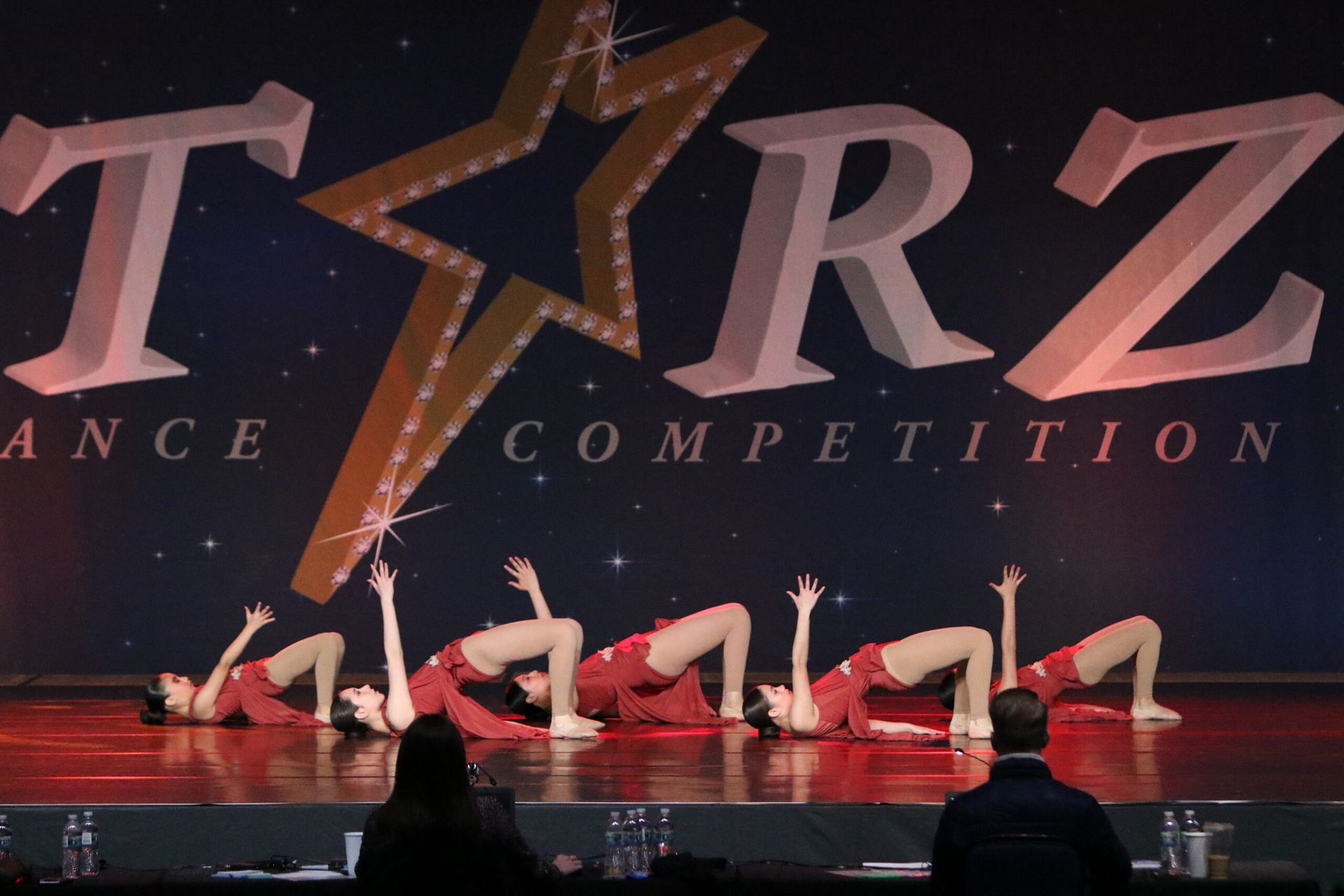 A group of dancers are performing in front of a sign that says tarz dance competition