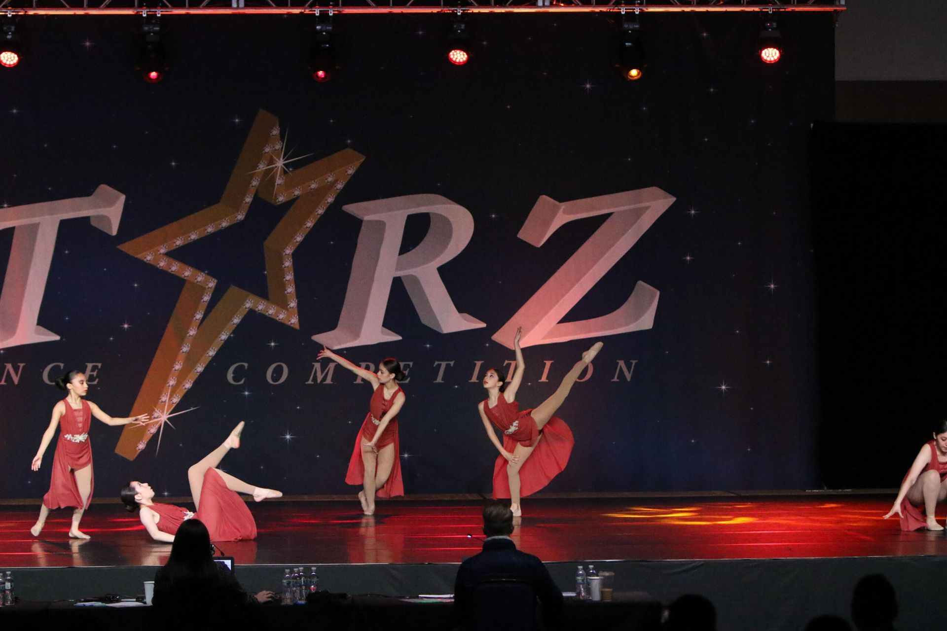 A group of dancers are performing on a stage in front of a sign that says tarz