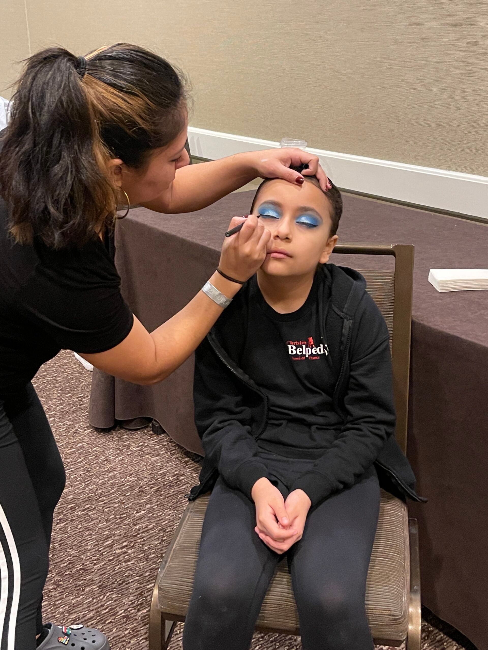 A woman is applying makeup to a young girl 's face.