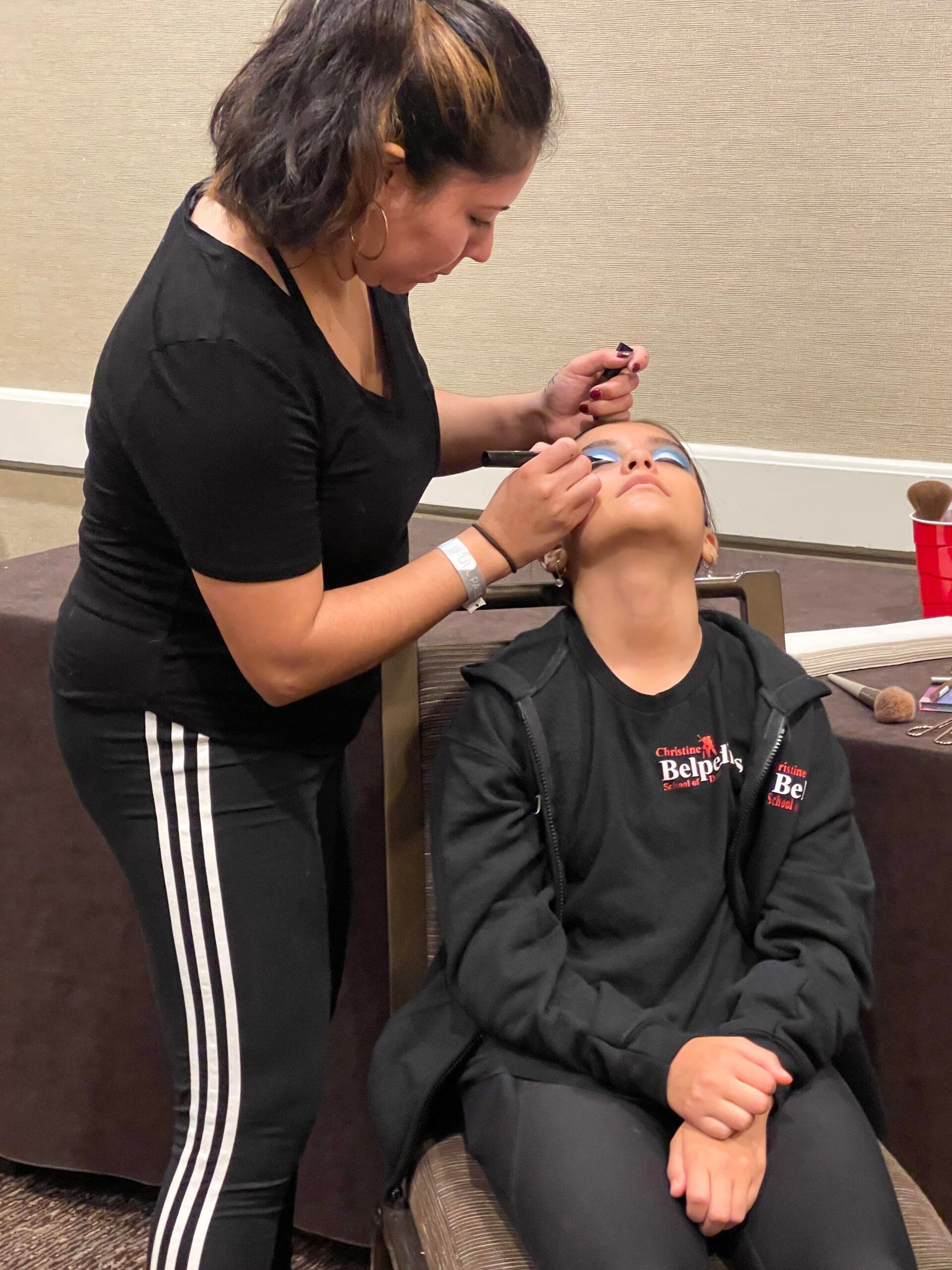 A woman is applying makeup to a young girl 's face.