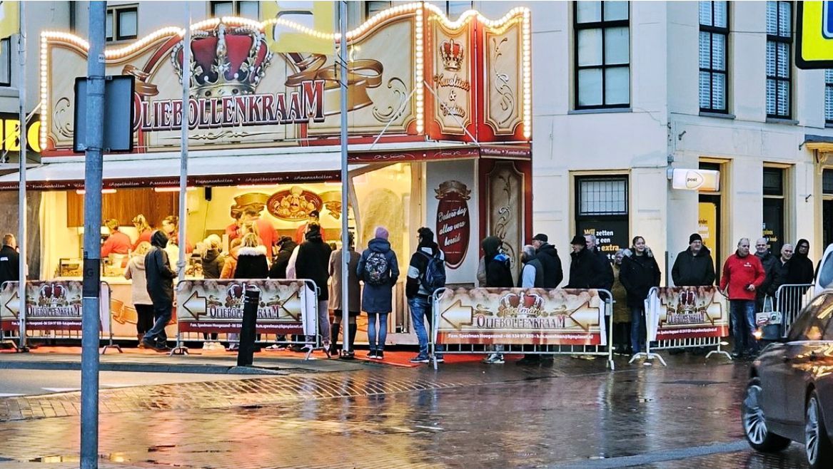 A group of people are standing outside of a carousel.