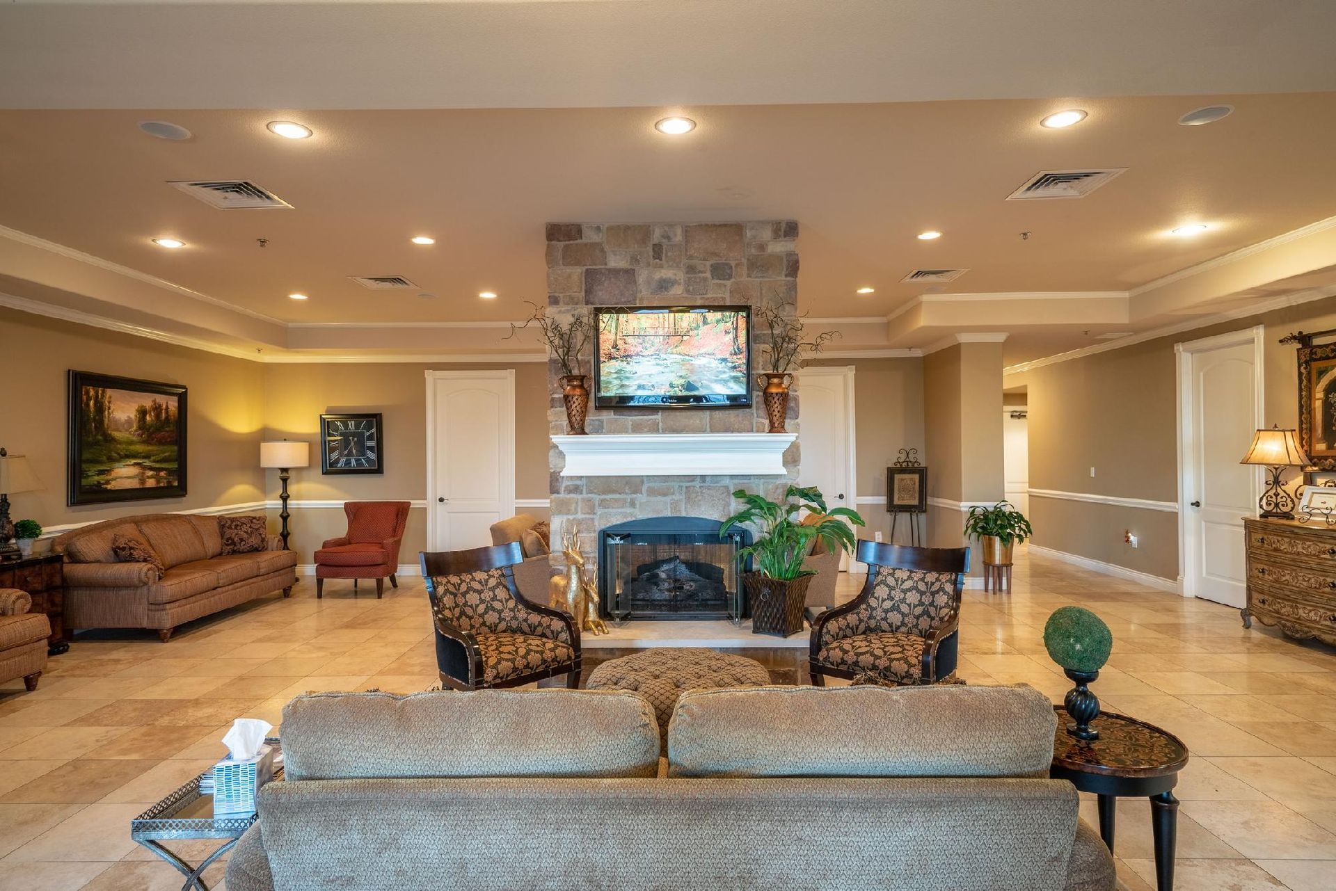 Spacious lobby with fireplace, TV, and seating. Neutral colors, stone accents, and marble flooring.