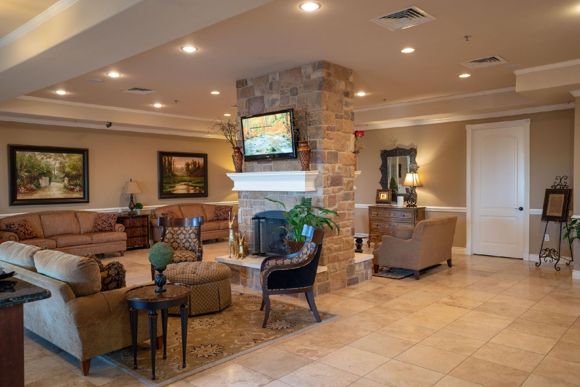 Spacious lobby with couches, stone fireplace, art, TV, and large windows.