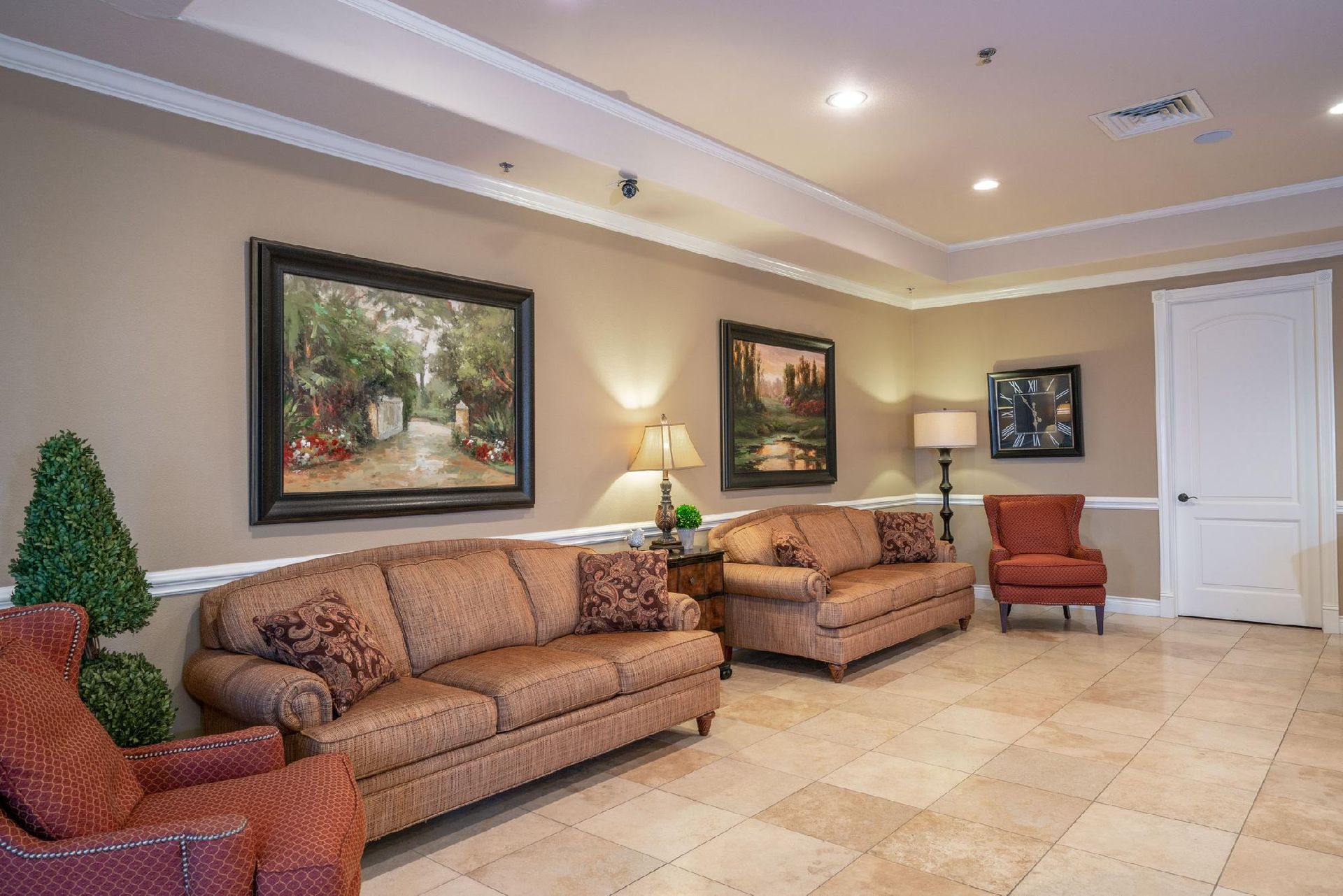 Lobby with seating, artwork, and neutral colors; featuring two sofas, two armchairs, and landscape paintings.