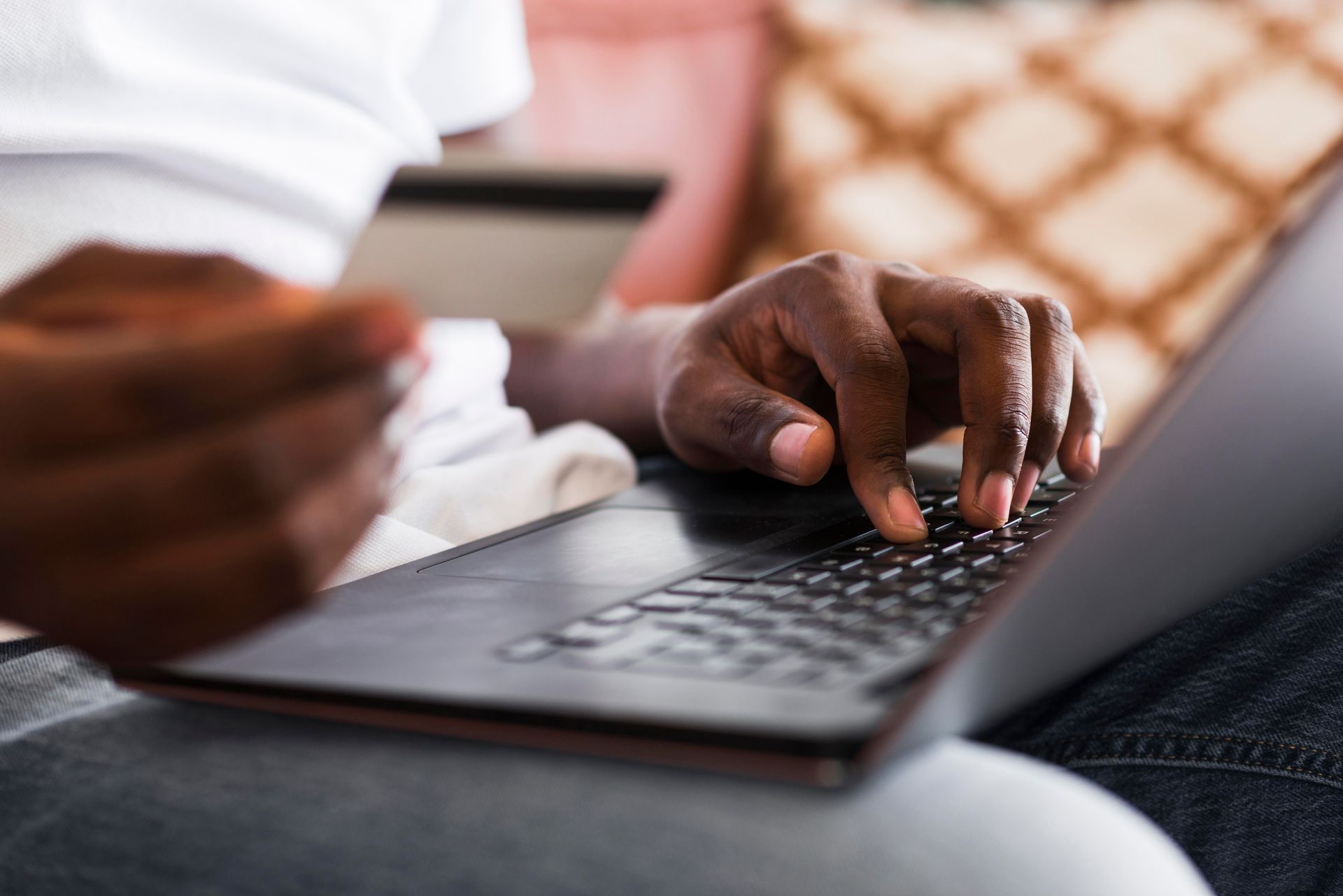 A person is typing on a laptop computer while holding a credit card.