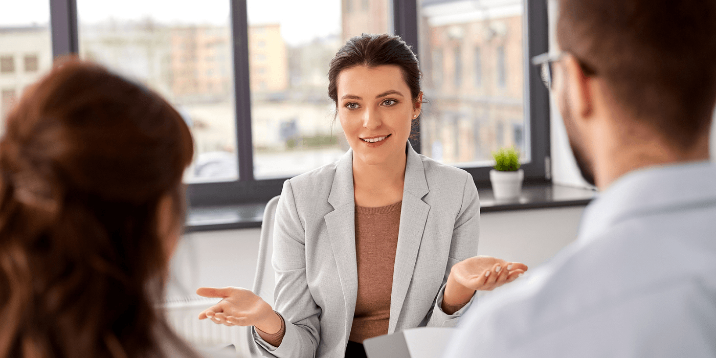 Woman speaking in a bright office during a business meeting, with two colleagues in the foreground