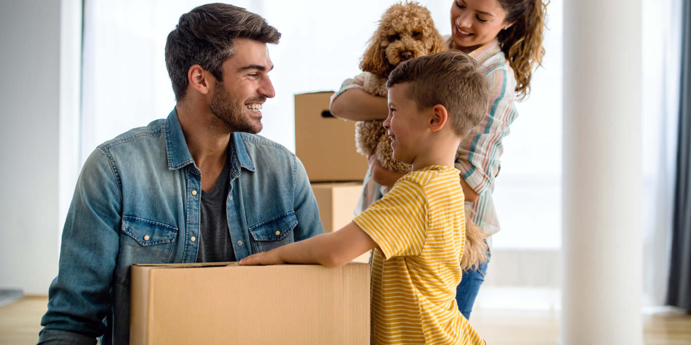 Family packing cardboard boxes in a bright room, with a man and two children talking and smiling