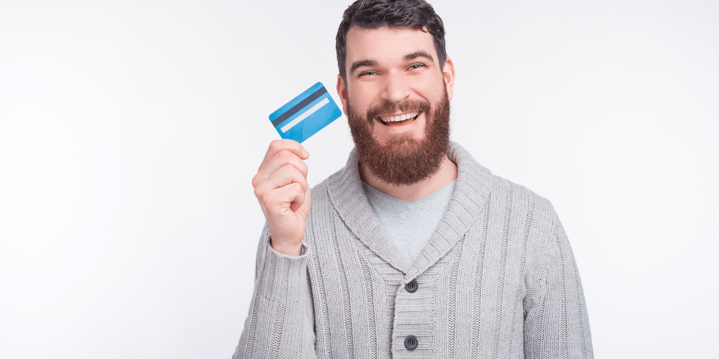 Smiling man holding a blue credit card against a white background