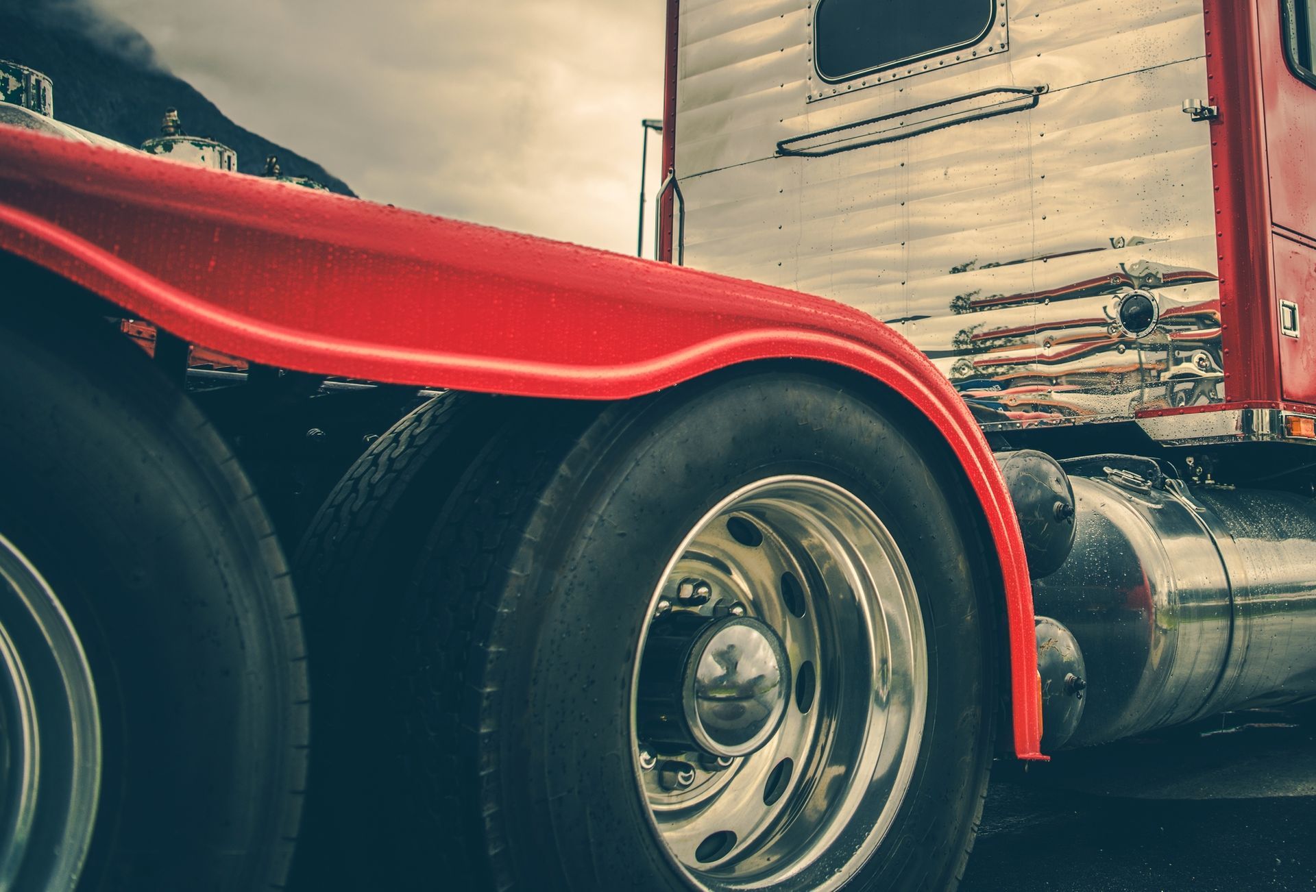 A red semi truck is parked next to a trailer.