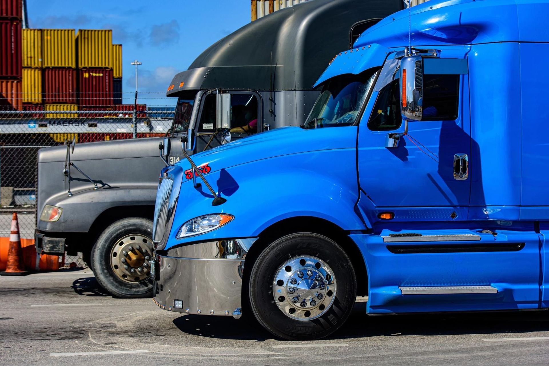 A row of semi trucks are parked next to each other in a parking lot.