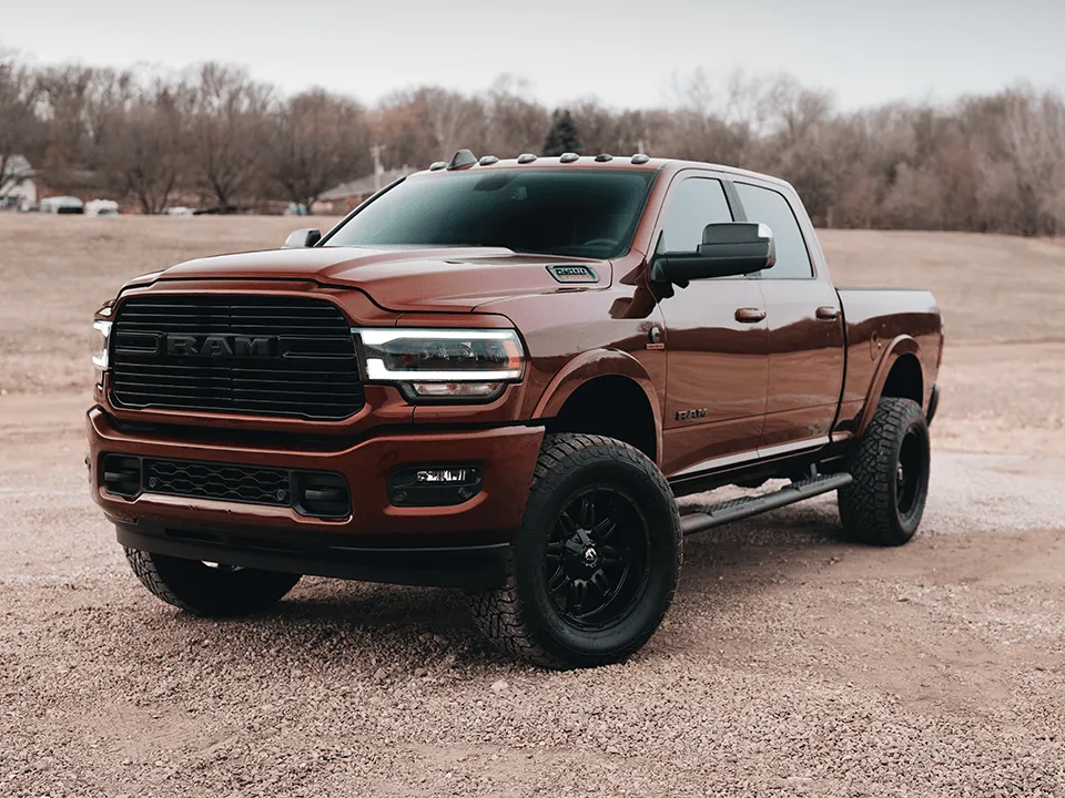 a red ram truck is parked in a dirt field .
