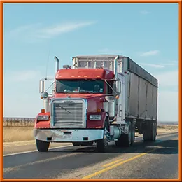 A red semi truck is driving down a highway.