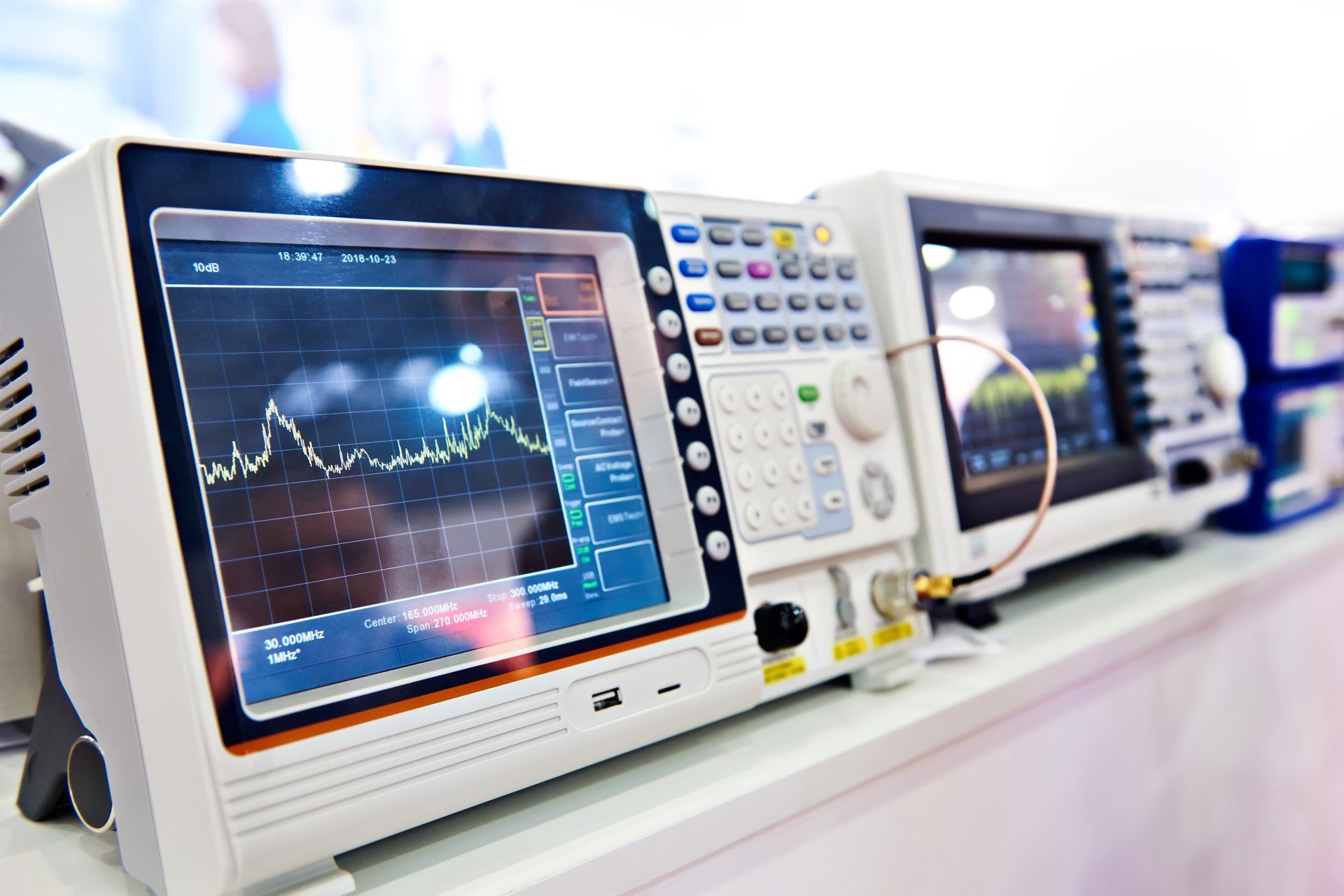 Electronic test equipment on a shelf, showing graphs and controls on their screens.