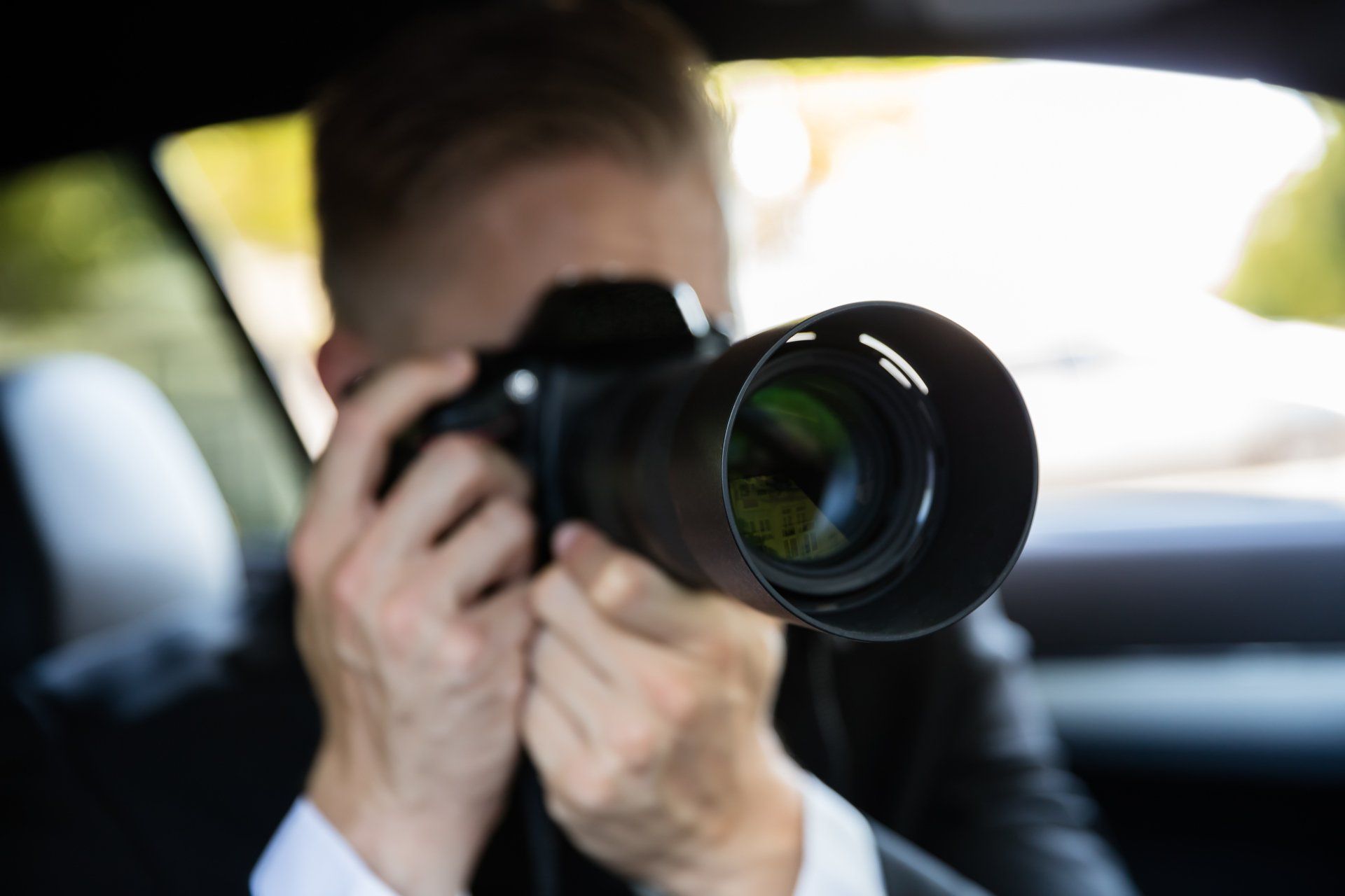 Person in car holding a camera with a long lens, possibly taking a photo.