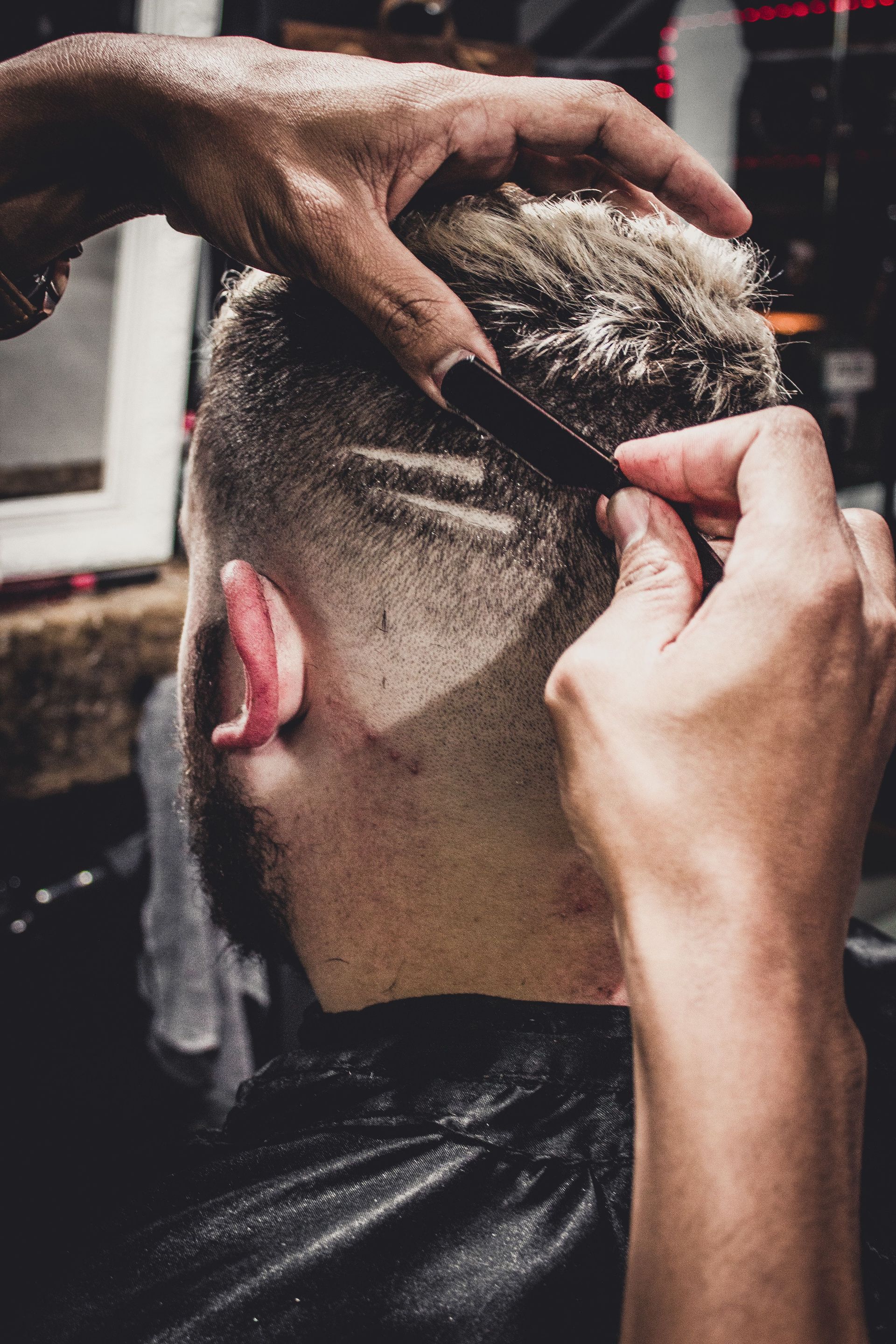 Barber trimming the back of a customer’s fade haircut with clippers and comb