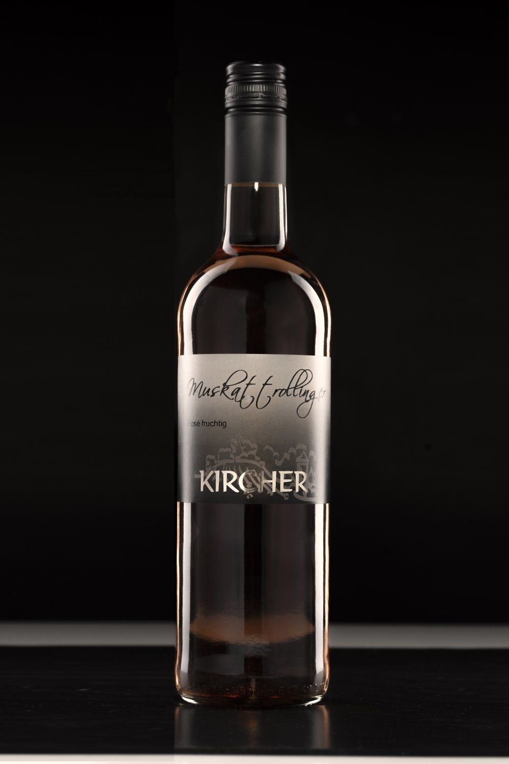 Eine Flasche Wein steht auf einem Tisch vor schwarzem Hintergrund.