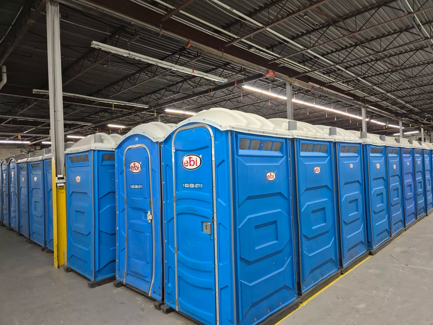 Rangée de toilettes portables bleues à l'intérieur d'un entrepôt.