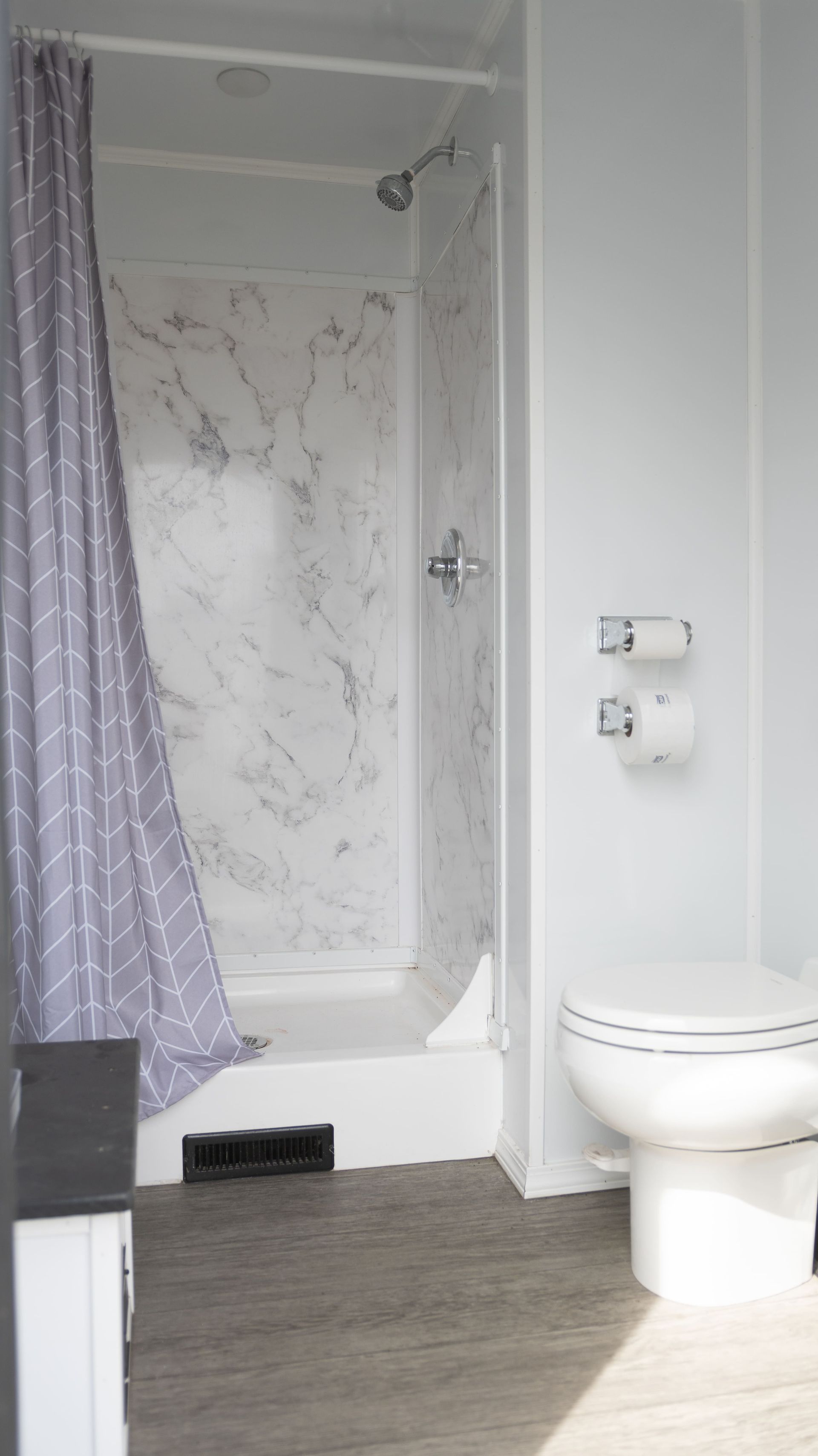 Remorque de toilettes portables blanches avec marches, logos rouges, stationnée à l'extérieur.