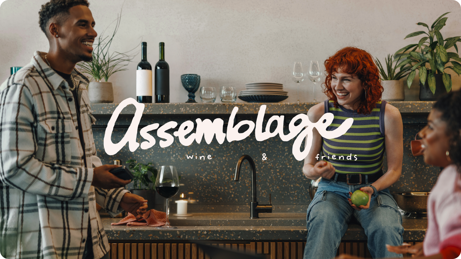 Two people in a modern kitchen with the word “Assemblage” overlaid in white script.