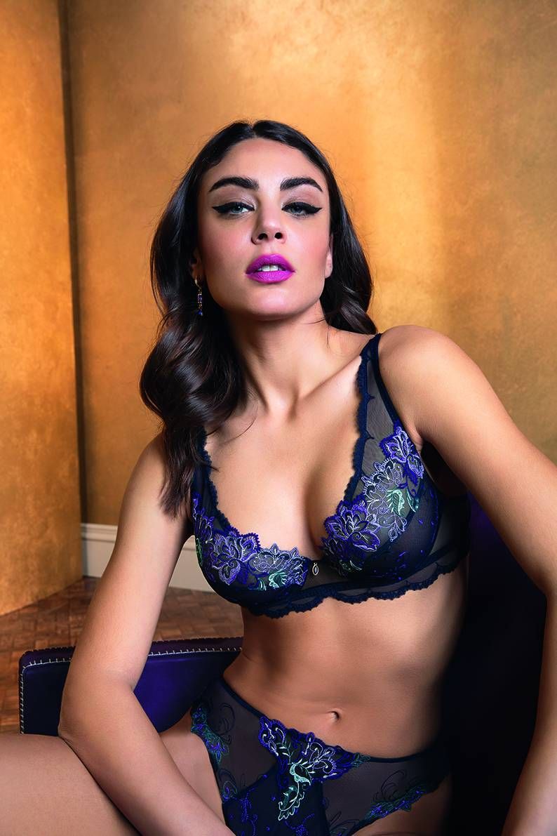 Femme en lingerie fine, cheveux noirs, rouge à lèvres audacieux, regardant droit devant elle.