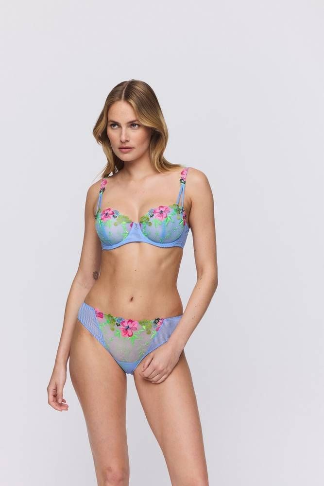 Femme en lingerie bleue à broderies florales, prenant la pose.