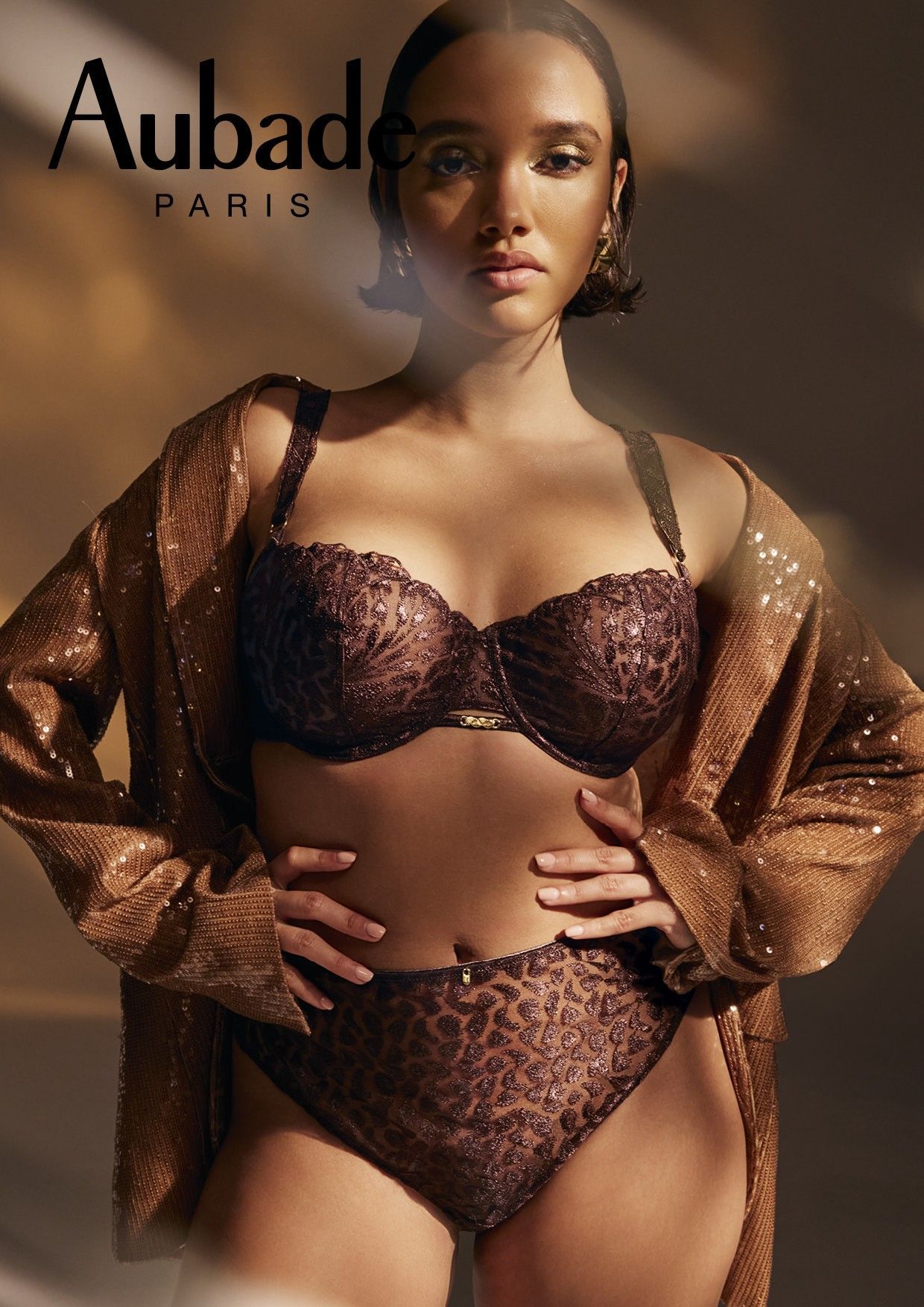 Femme portant de la lingerie marron et une veste à paillettes, logo Aubade Paris.