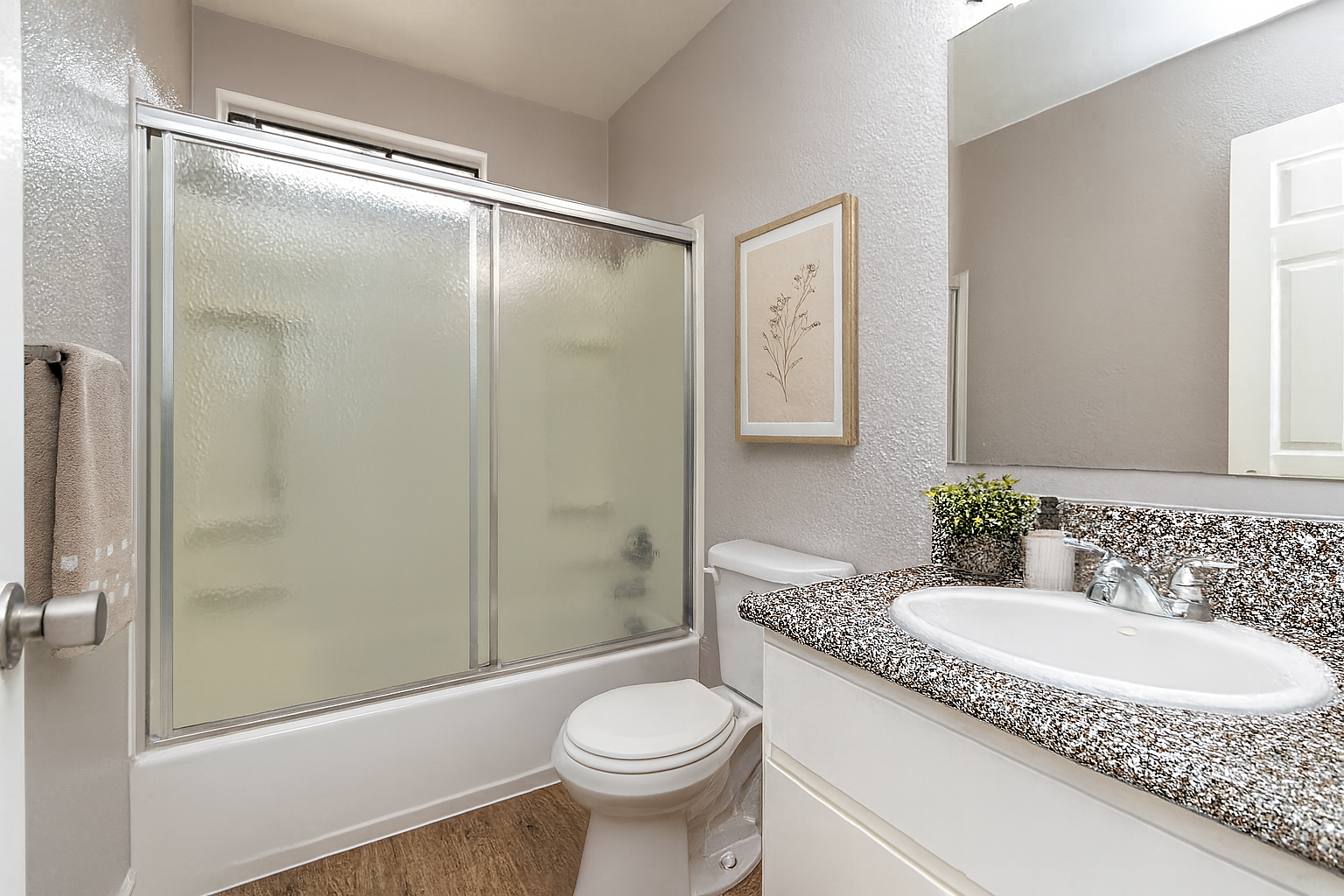 Small bathroom with frosted-glass shower, toilet, and sink vanity with mirror.