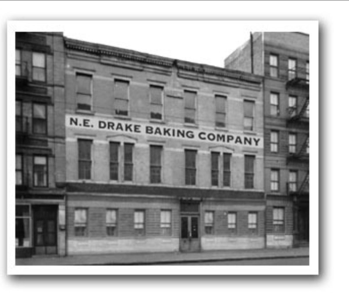 A historic black-and-white photo of a multi-story building labeled N.E. Drake Baking Company.