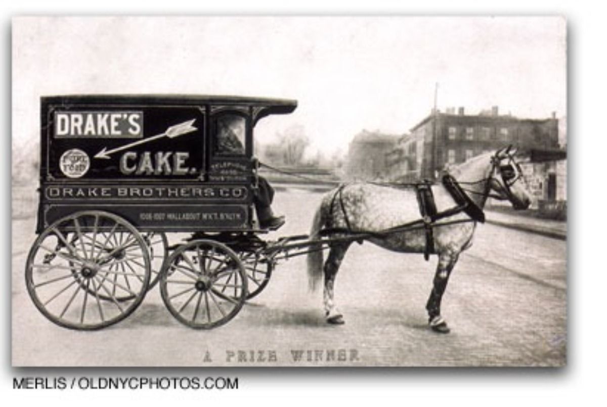 A vintage, black-and-white photo of a horse-drawn delivery wagon branded