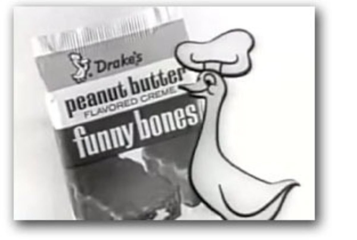 A black-and-white image of a Drake's Funny Bones snack cake package next to its mascot, a cartoon duck wearing a chef's hat.
