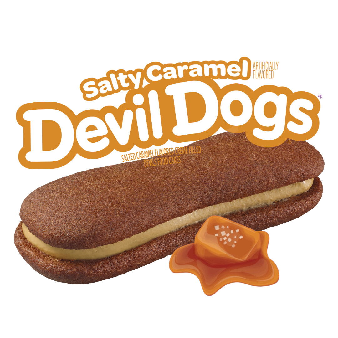 A Drake's Salty Caramel Devil Dog cake with a caramel pieces beside the cake against a white background.