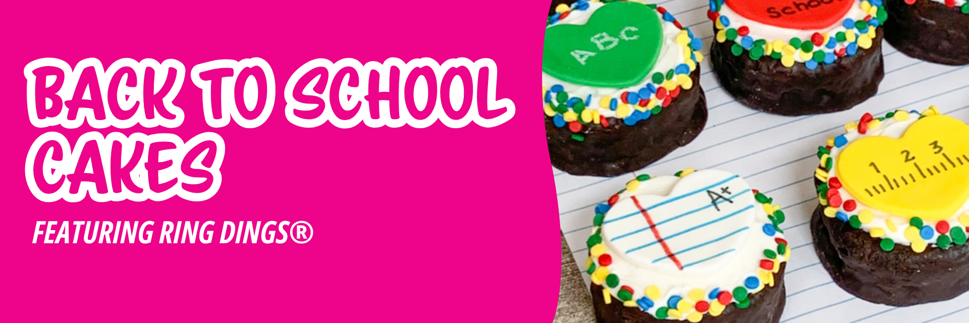 Pink banner promoting small round cakes decorated for school, featuring icing designs like lined notebook paper, rulers, and apples on a desk.