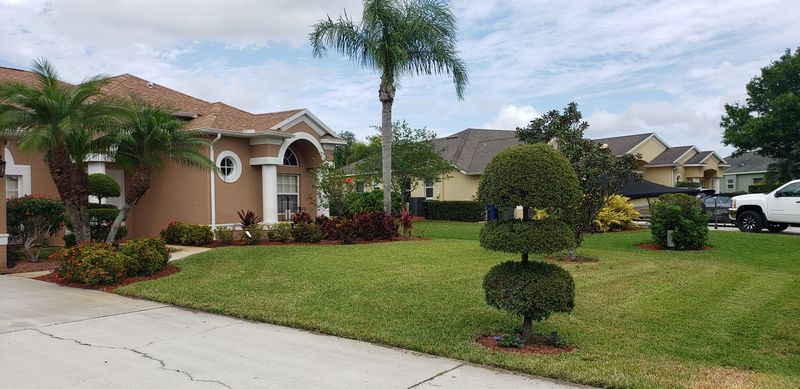 A house with a lush green lawn and a white truck parked in front of it.