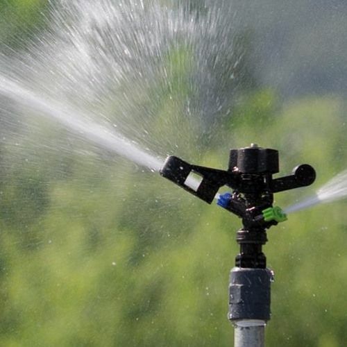 A close up of a sprinkler spraying water in a field.