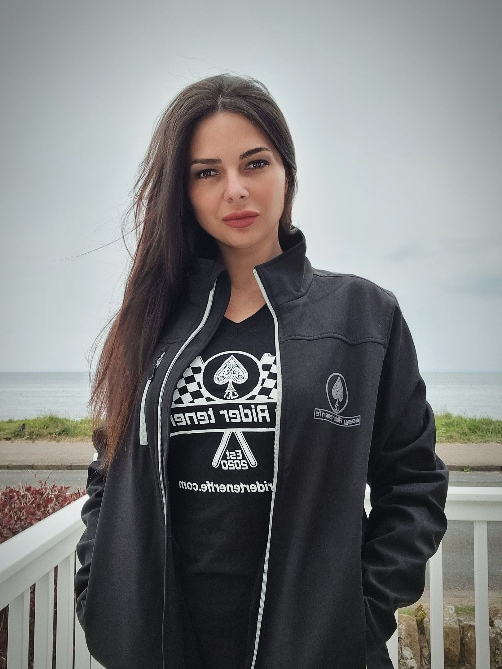 A woman wearing a black jacket and a t-shirt with a spade on it