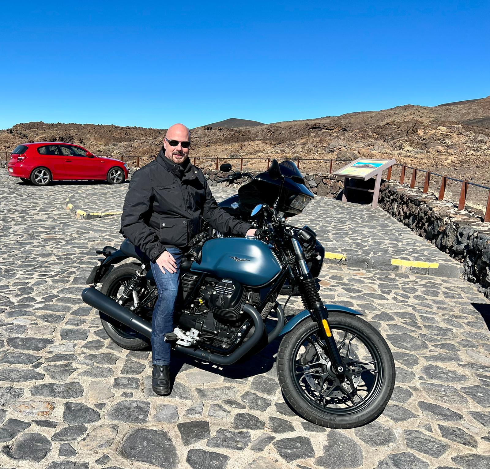 A man is sitting on a motorcycle on a cobblestone road.