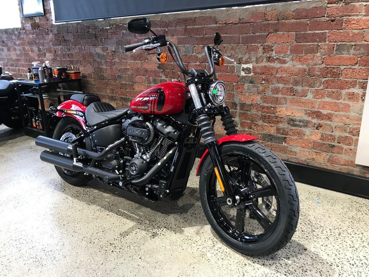 A red motorcycle is parked in front of a brick wall in a garage.