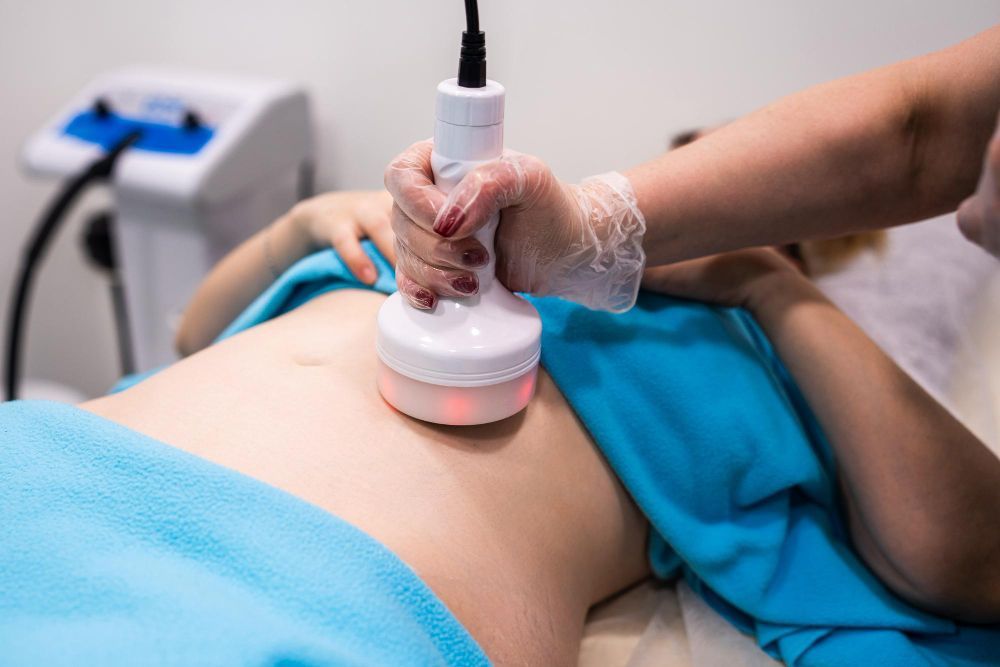 Therapist using handheld ultrasound device on a patient’s abdomen during treatment