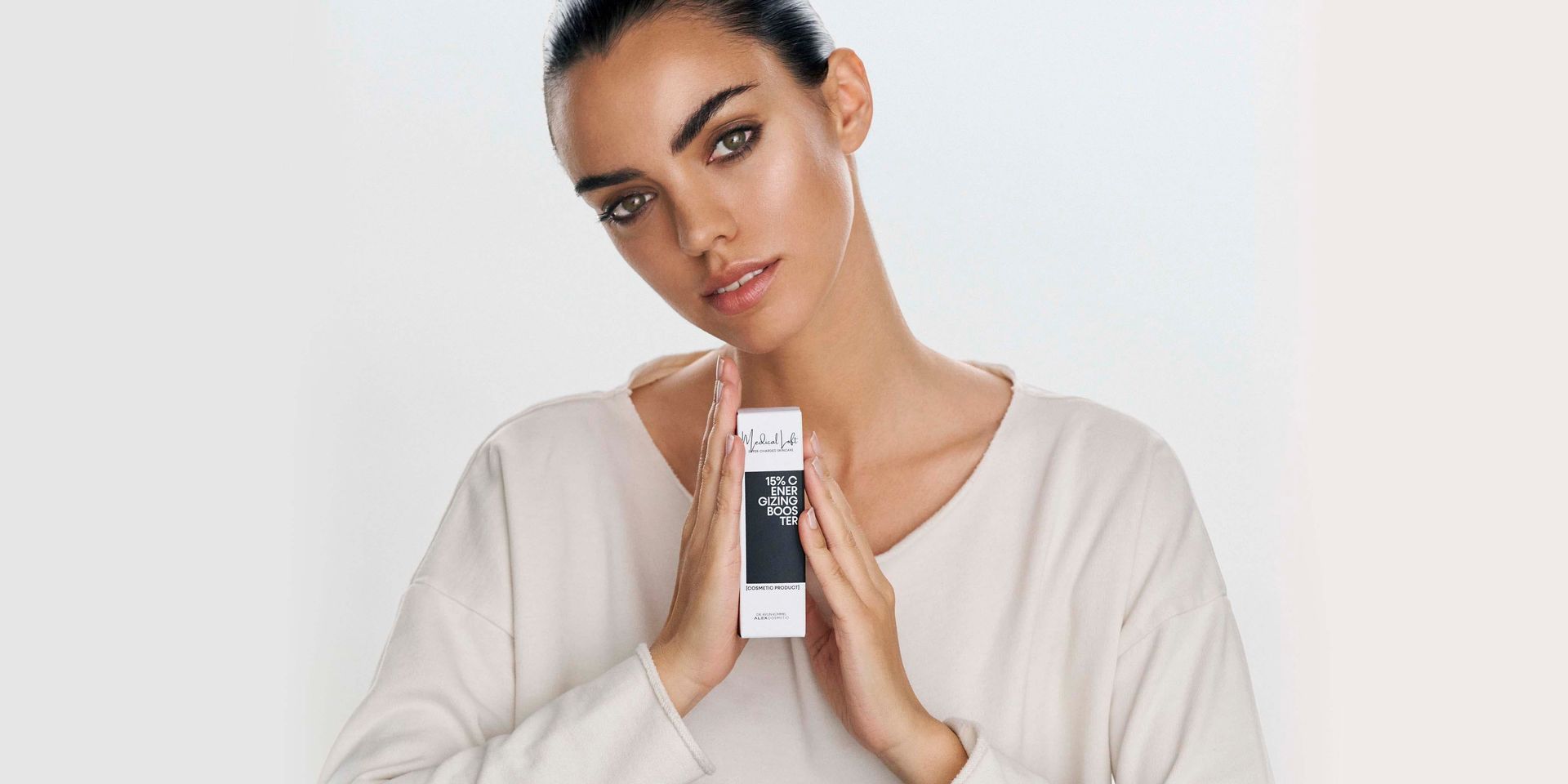A woman in a white sweater is holding a box in her hands.