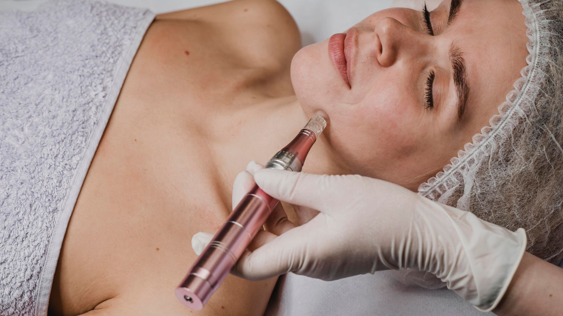 Cosmetic injection being administered to a woman’s neck while she reclines under a towel