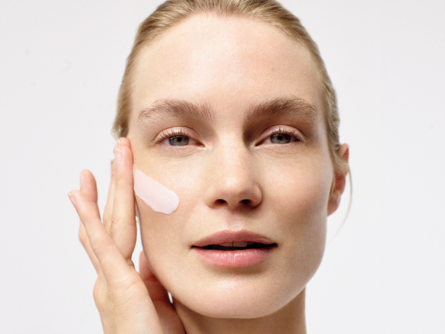 A woman is applying a cream to her face.