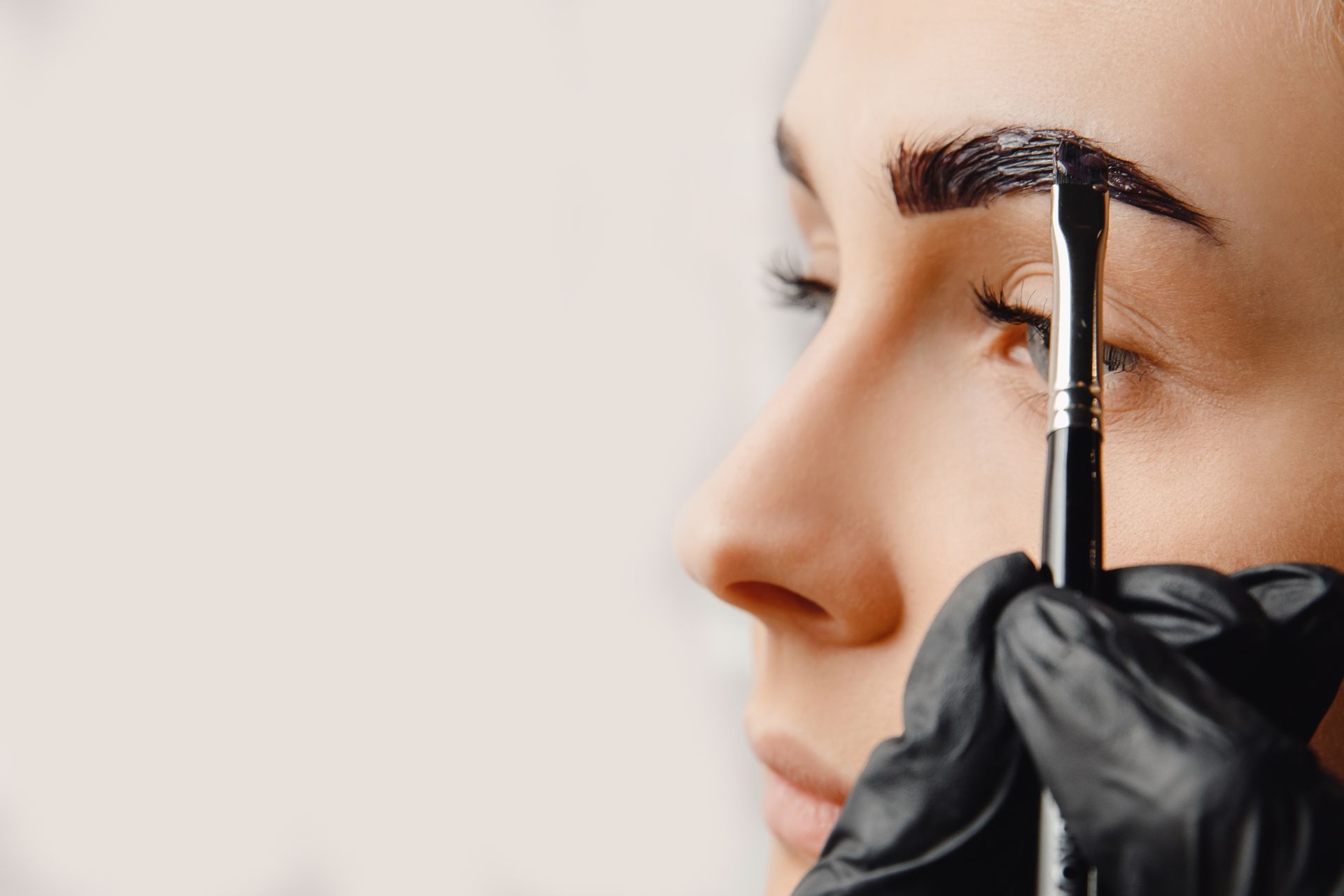 A woman is getting her eyebrows painted with a brush.